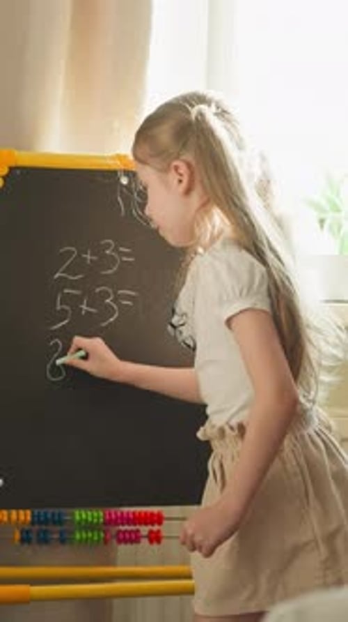 Girl Writes Math Problems for Brother Playing School at Home