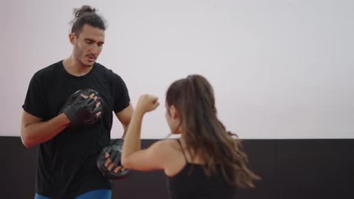 Woman Boxing with Coach in Training Room