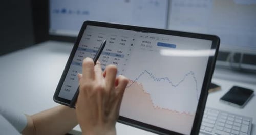Person Analyzing Stock Market Charts on Tablet