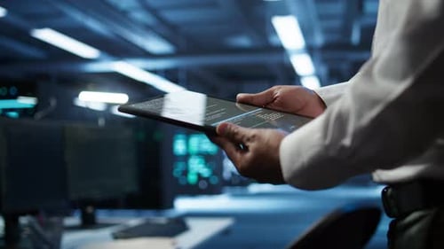 Close Up of Tablet Used By IT Worker Doing Maintenance on Server Farm Gear