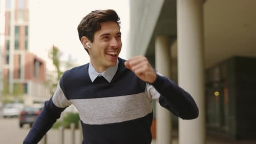 Fröhlicher glücklicher Geschäftsmann tanzt, geht draußen spazieren und hört Musik