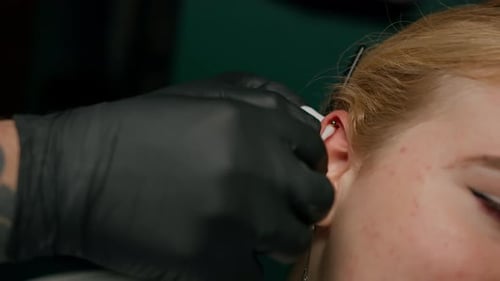 Piercing studio interior - piercing master makes a piercing to a girl, ear piercing