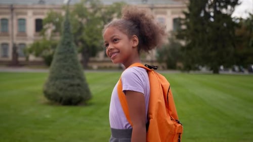 Kleines Mädchen, Afroamerikaner, glücklich lächelnd, mit Rucksack, geht zurück zur Schule