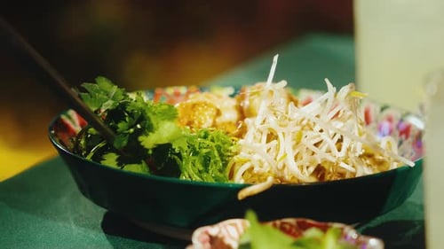 Garnishing Pad Thai Noodles with Fresh Herbs and Peanuts