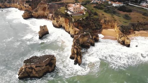 Breathtaking Aerial View of Rugged Golden Cliffs and Ocean Waves