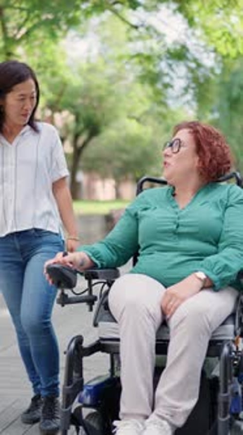 Two Women Walking in a Park, One in Wheelchair