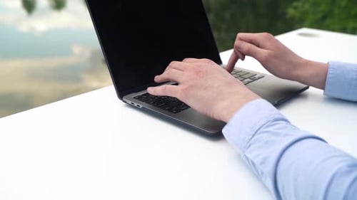 A man works with a laptop near the river