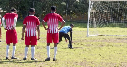 Playing soccer, player preparing to kick ball towards goal with goalkeeper ready