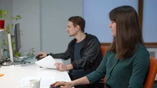 Young Positive Woman Talking to Blurred Man Sitting at Table in Office