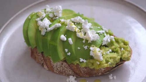 Preparing Gourmet Avocado Toast With Cheese and Oil