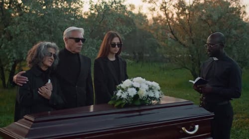 Relatives Listening to Priests Burial Service at Cemetery