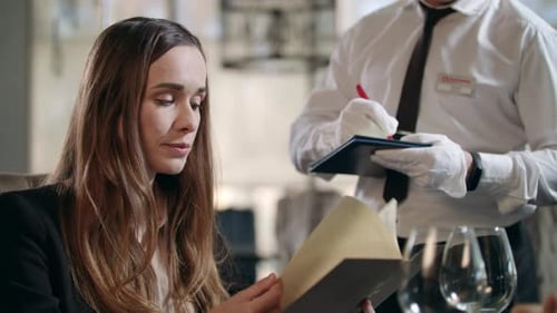 Business Woman Choosing Food Menu in Restaurant. Pretty Woman Talking with Waiter