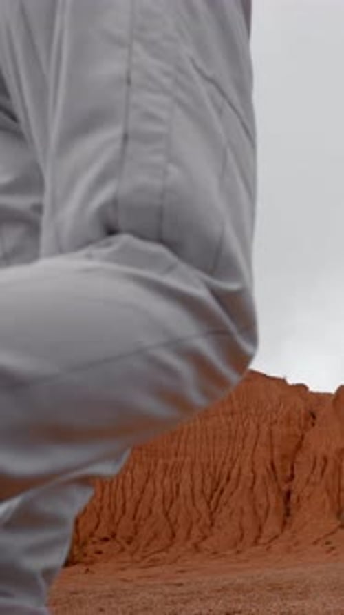 Vertical of Unrecognisable Astronaut in Costume and Helmet Walking on Mars Orange Surface