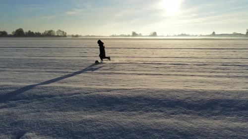 Little boy playing with a ball in field full of snow