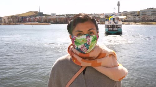 Stockholm, Sweden, coronavirus. Portrait of woman wearing a colorful safety mask. Ferryboat is saili