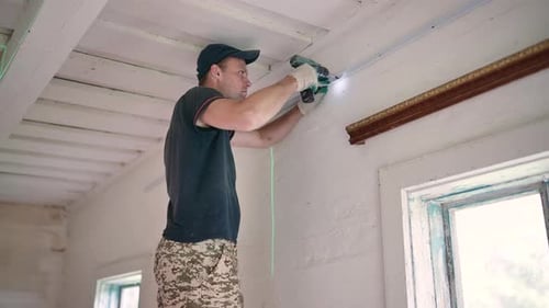 An Electrician Works with a Drill to Create Electrical Wiring