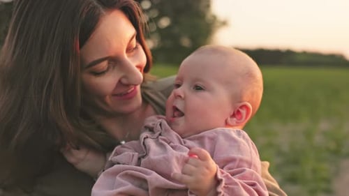 Happy Baby Sitting in Mother's Arms Closeup Shot of Young Goodlooking Woman Kissing Lovely Daughter