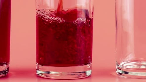 Le
jus de grenade est versé dans des gobelets en verre sur fond rose. Ralenti.