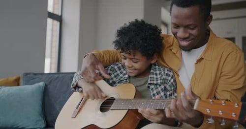 Happy Child Learning Guitar with Smiling Adult