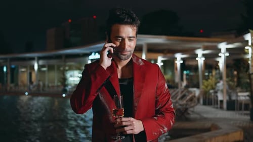 Man with Champagne Talking on Phone at Night