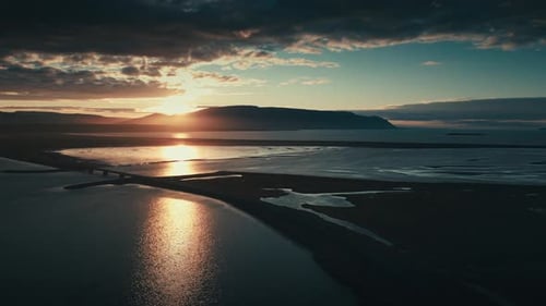 Incredible and epic drone and aerial shot of the setting sun against a bridge and series of lakes wi
