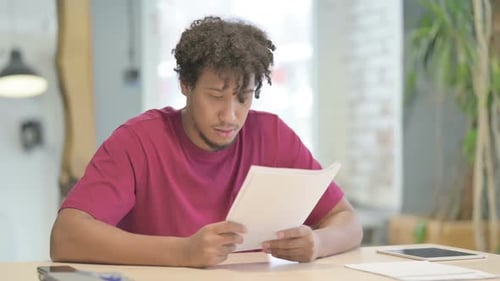 African Man Upset while Reading Documents in Office