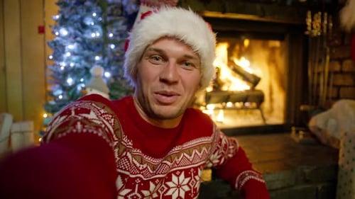 Man Smiling in Santa Hat Beside Christmas Tree