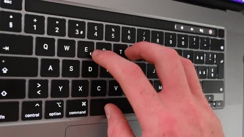 Ein Texter arbeitet hinter seinem Laptop, tippt auf der Tastatur, Online-Nachrichten