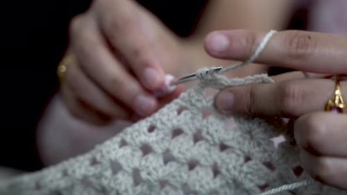 Woman crocheting with white thread using crochet hook. close up