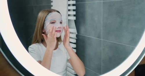 Girl Applying Sheet Face Mask in a Bathroom