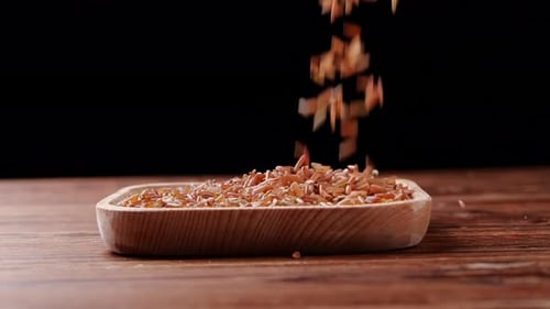 Pouring Brown Rice into a Light Brown Wooden Bowl
