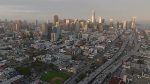 Atemberaubende Panoramaaufnahme von Wolkenkratzern in der Innenstadt, die von der untergehenden Sonne beleuchtet werden, Stau auf mehrspurigen Straßen