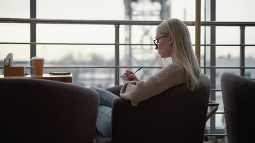 Seitenansicht einer sitzenden Frau mit Buch am Tisch in einer gemütlichen Umgebung