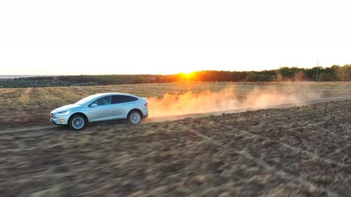 Car Driving Through a Rural Field at Sunset