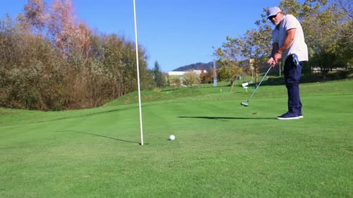 Senior golfer making precise putt on green for triumphant shot