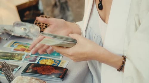 Woman Shuffles Tarot Cards at Outdoor Table