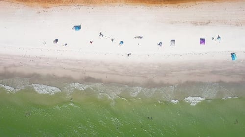 Top-down view of sandy shoreline with umbrellas and turquoise water