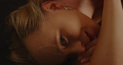 Close up of a beautiful blond woman lying down and seductively looking at camera