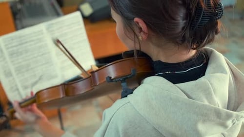 Side or Back View of Student Playing Violin During Exam Preparation