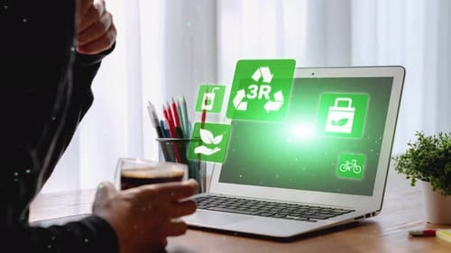 Man drinks coffee while reviewing sustainability icons on laptop