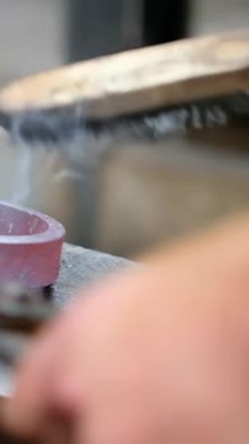 Vertical video: Brushing worker hands contacting red disk with wire brush, removing metal dust