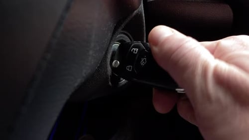 Hand inserts modern car key into ignition