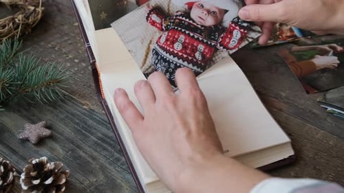 Las manos ponen fotos familiares navideñas en un álbum de fotos