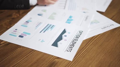 Close Up of a Businessman Hands with Pen Working at Office Desk and Analyzing Graphs and Charts and