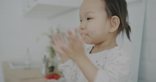 Zeitlupenporträt eines entzückenden kleinen Babys, das zu Hause in der Küche in die Hände klatscht und lacht
