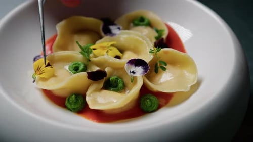 Yellow And Purple Flowers Over A Stuffed Pasta Dish