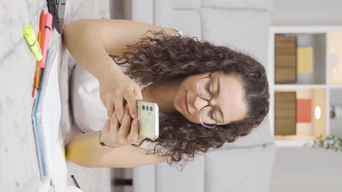 Young Adult Looks at Smartphone and Writes