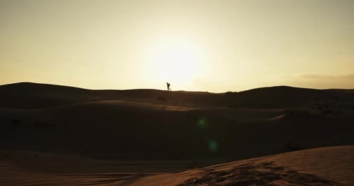 Wide Shot of Man Walking on Sand Dunes at Sunrise in Oman Desert