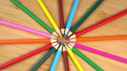 Los lápices de colores giran como fondo de rayos solares. Lápices arcoíris para dibujar. Surtido de colores