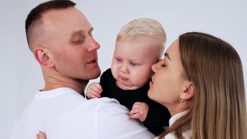 Loving Parents Kissing Cute Baby Indoors
